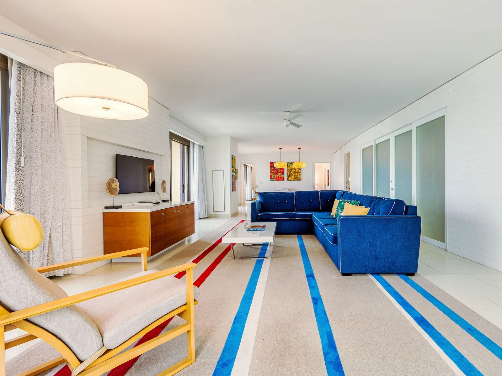 The Governor Suite’s living room: a long space with a blue corner sofa, a rug striped in red and pale blue and a yellow armchair.