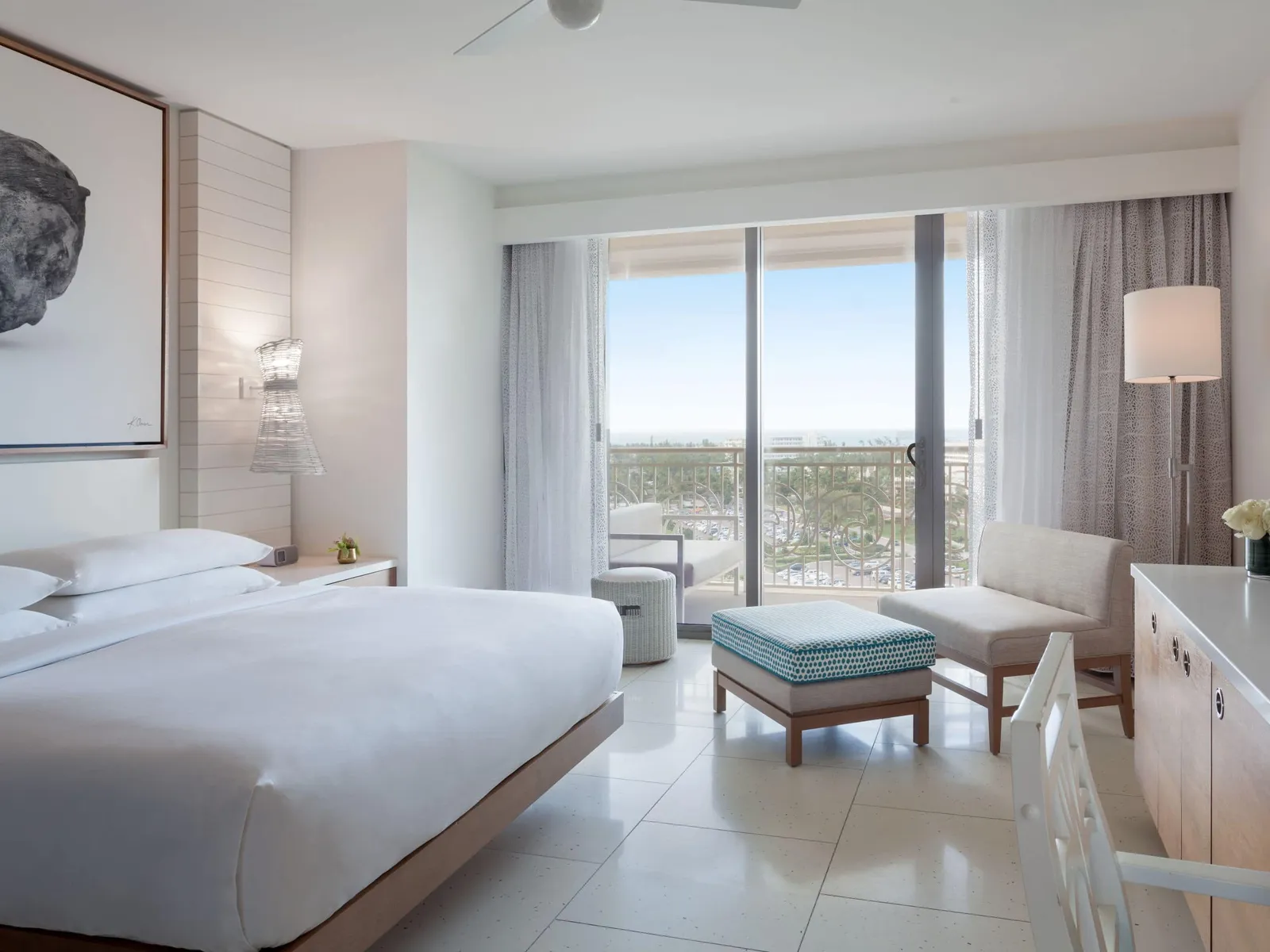 The bedroom of the Grand Suite King: the bed, a pale-blue footstool, 2 low chairs and the glass door to the balcony.
