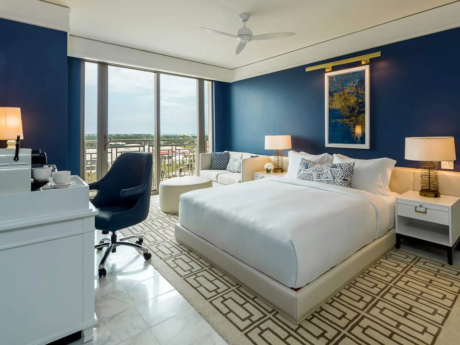 A Deluxe king room in the East Tower, with blue walls, the white desk and floor-to-ceiling windows looking inland.