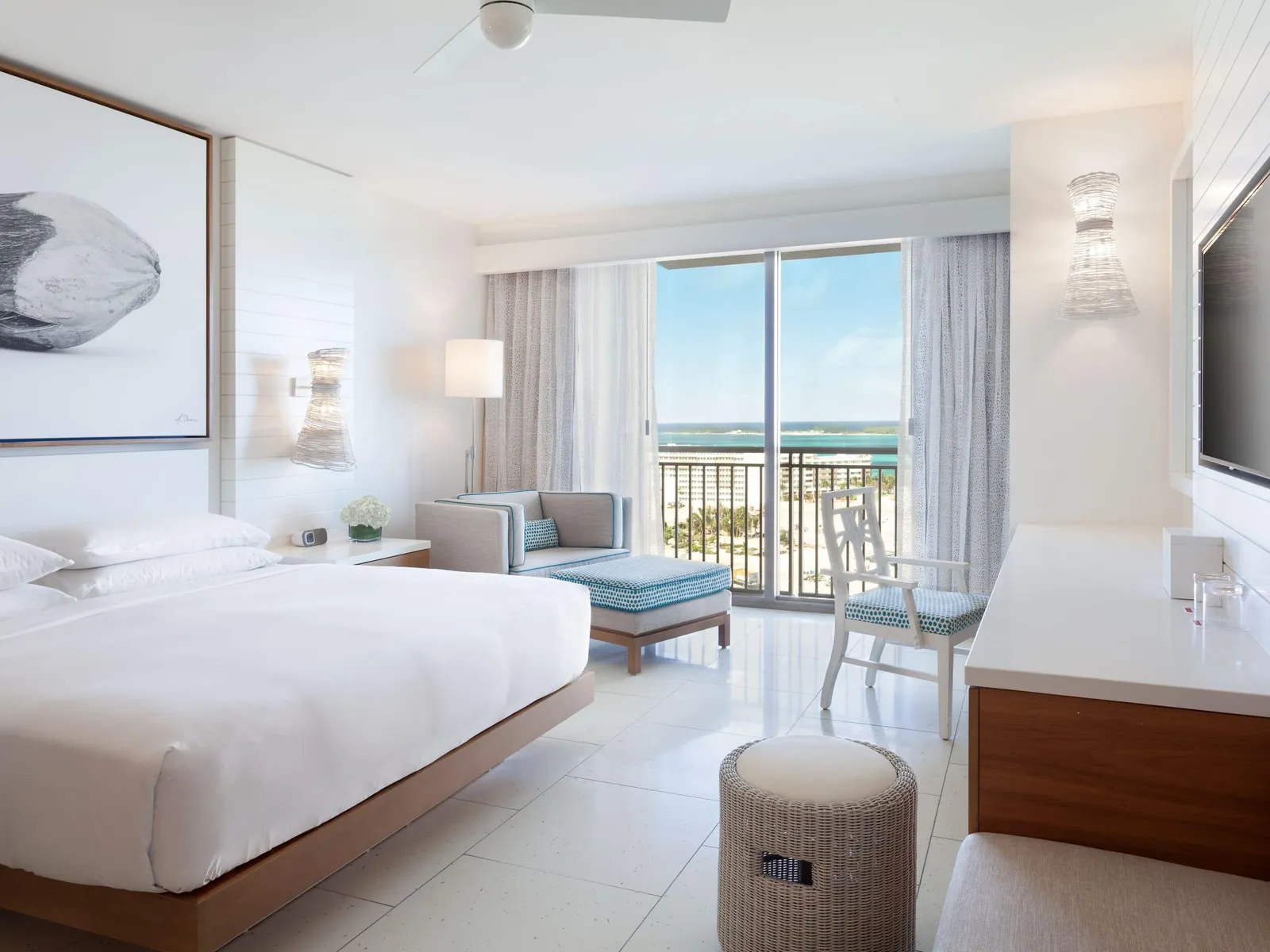 The bedroom of an ocean-view residence in the West Tower: the king bed, the pale-blue chaise and the glass door over the beach.