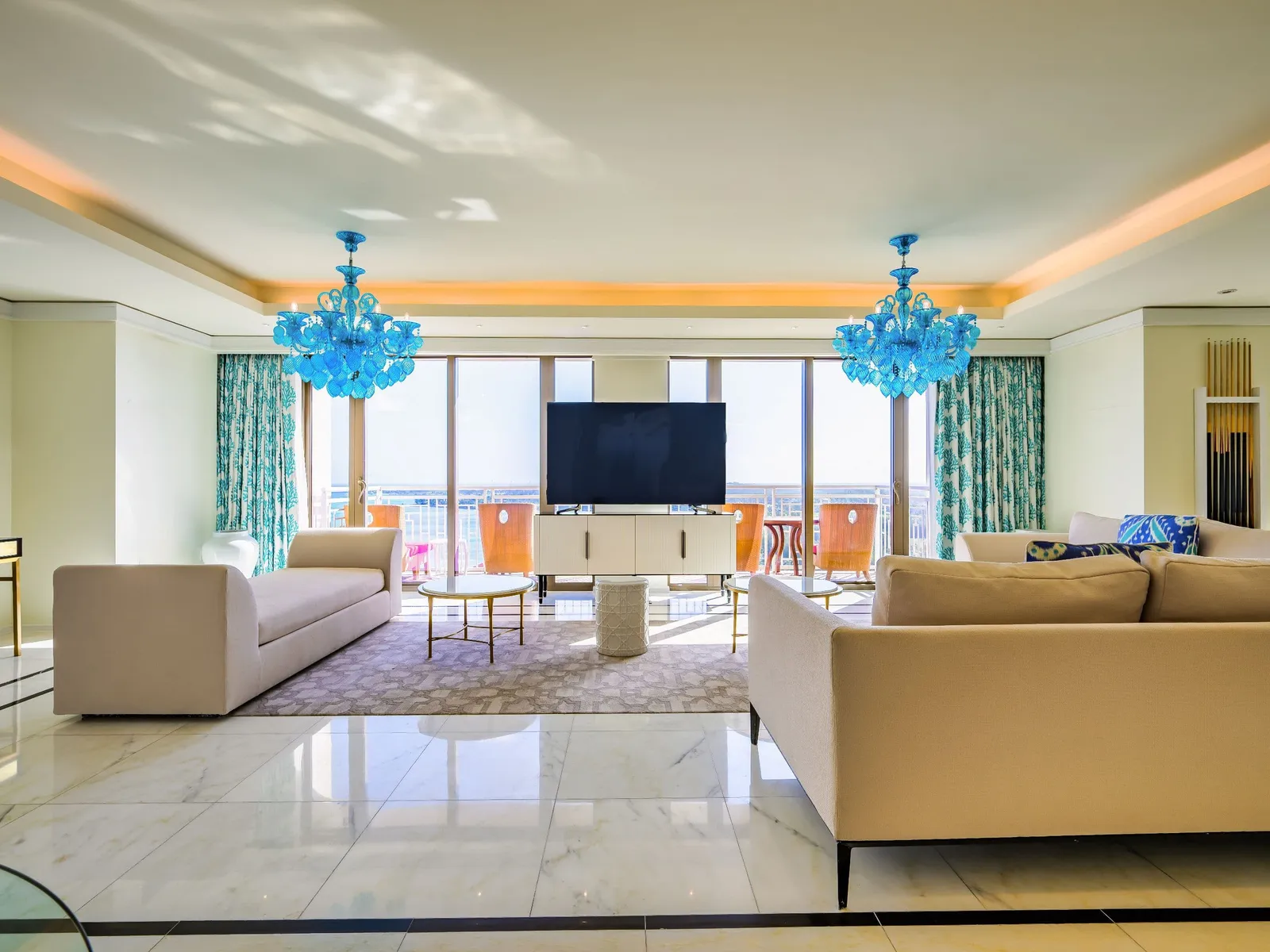 The Presidential Suite’s living room: 2 pale sofas, 2 blue glass chandeliers, turquoise curtains and the windows over the sea.