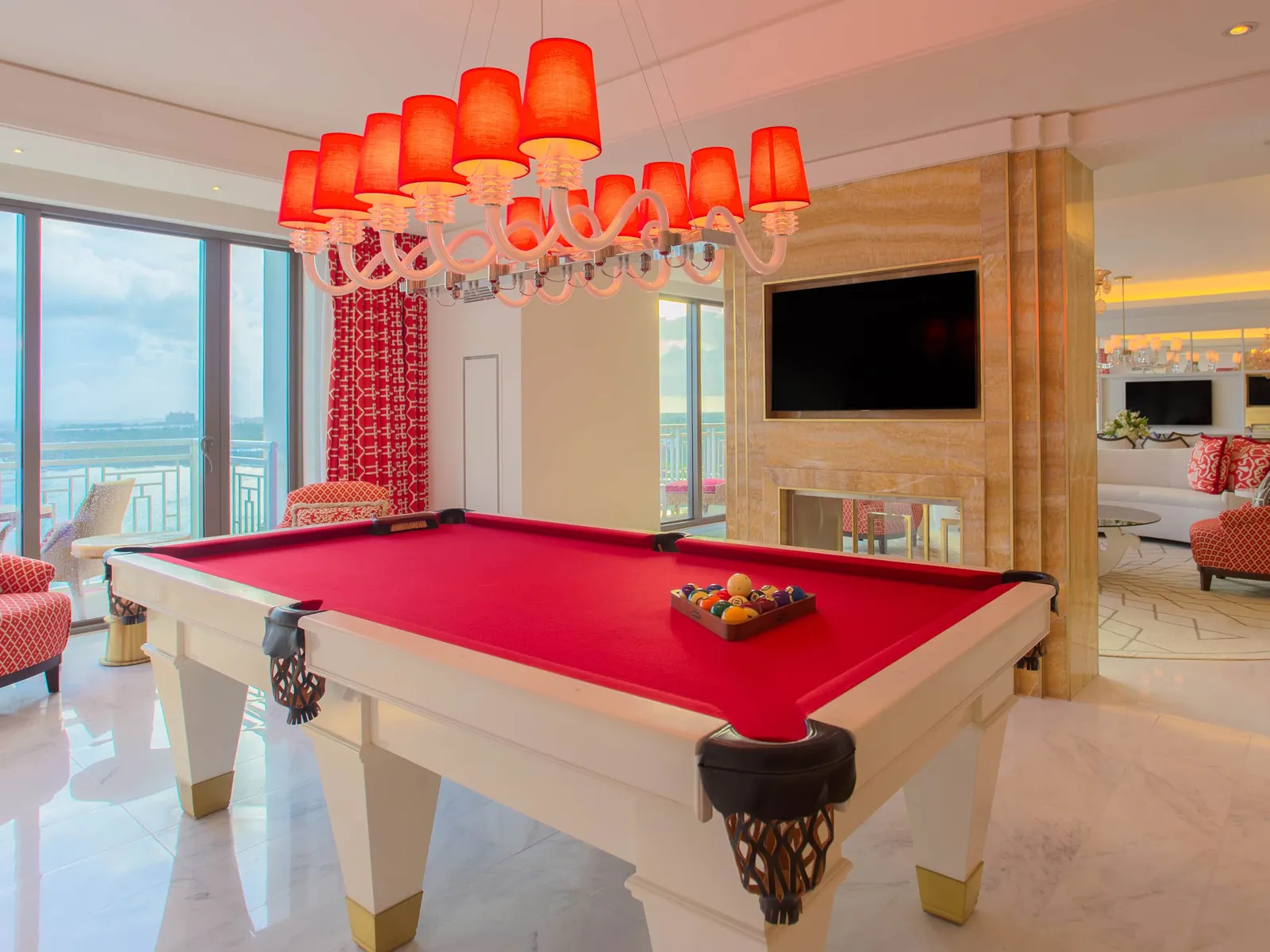 The red-baize billiards table of the Monaco residence, under a chandelier of red shades, with the fireplace and the windows over the sea.