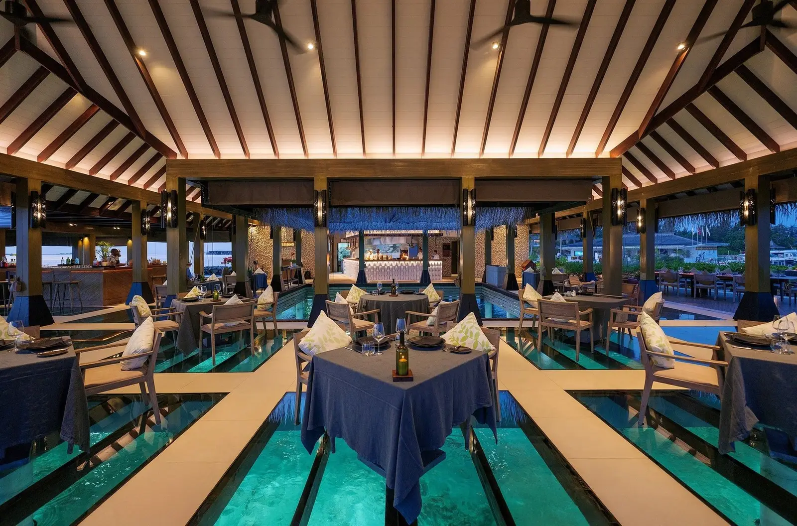 FireDoor’s dining room, its blue-clothed tables above the lit glass panels of the floor over the water.