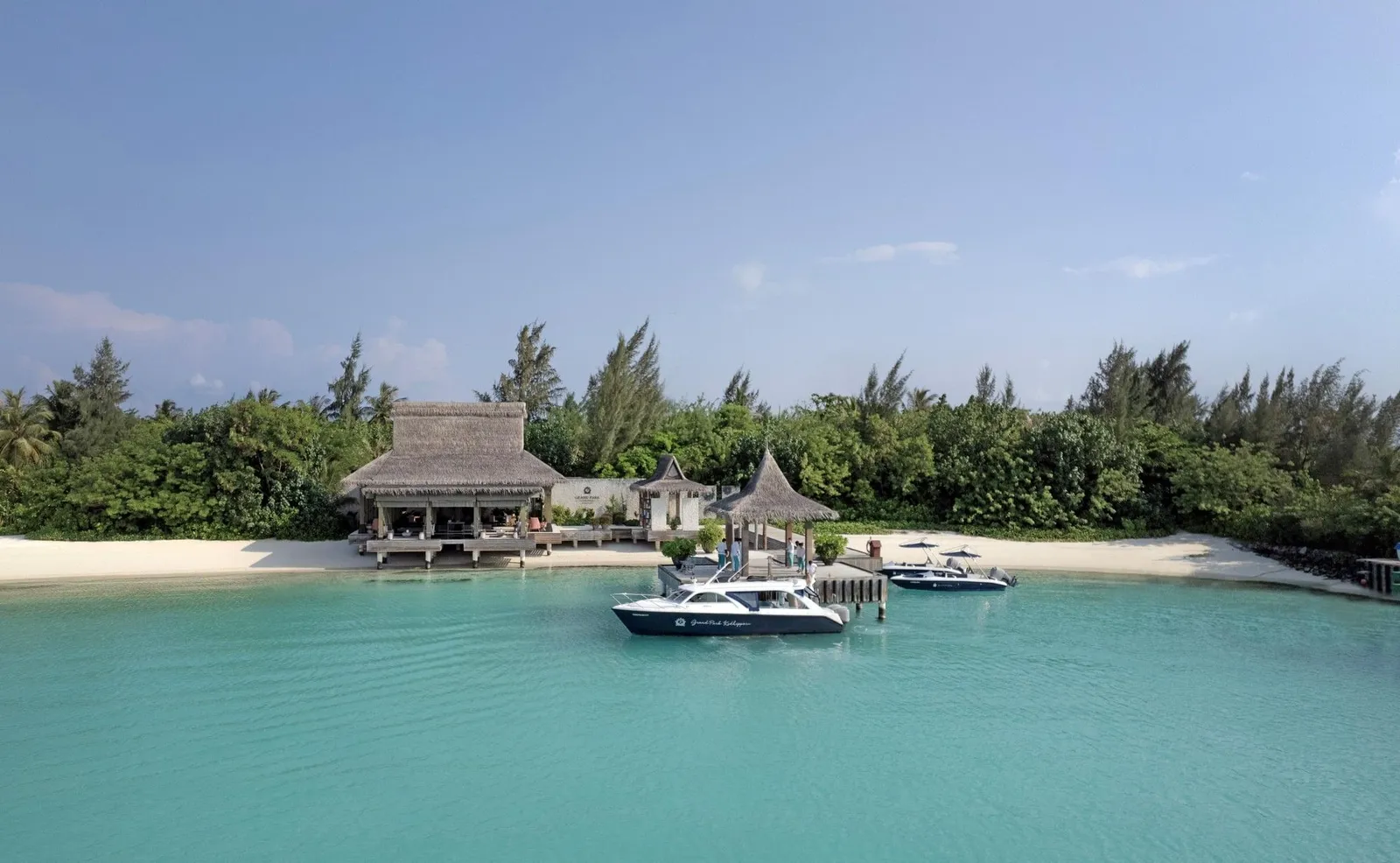 The arrival jetty: 2 speedboats moored in the shallow lagoon in front of the thatched pavilion and the beach.