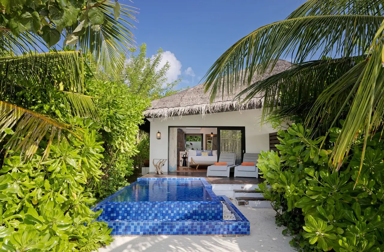 A Beach Pool Villa among the greenery: the thatched roof, the blue-mosaic private pool and the deck.
