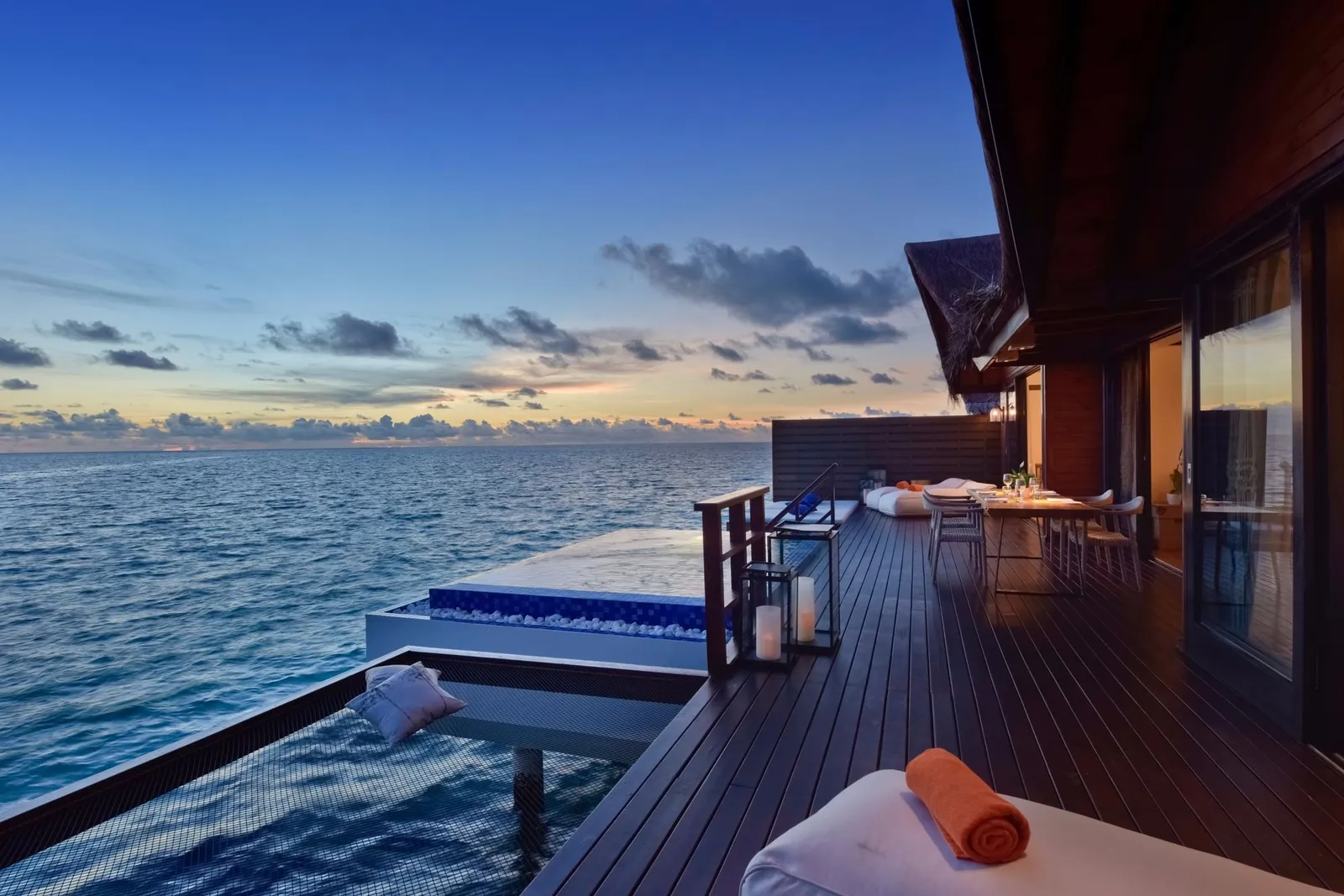 The Grand Residence deck at sunset, with its infinity pool, the loungers and the ocean.