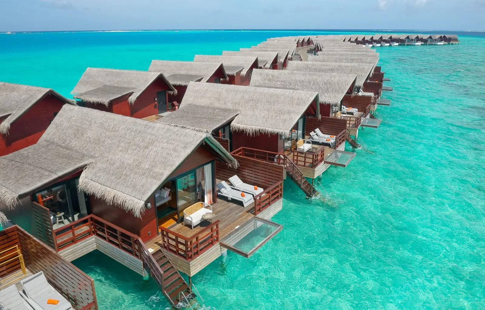 The Ocean Water Villas from above: the row of thatched roofs and decks over the water facing the open sea.