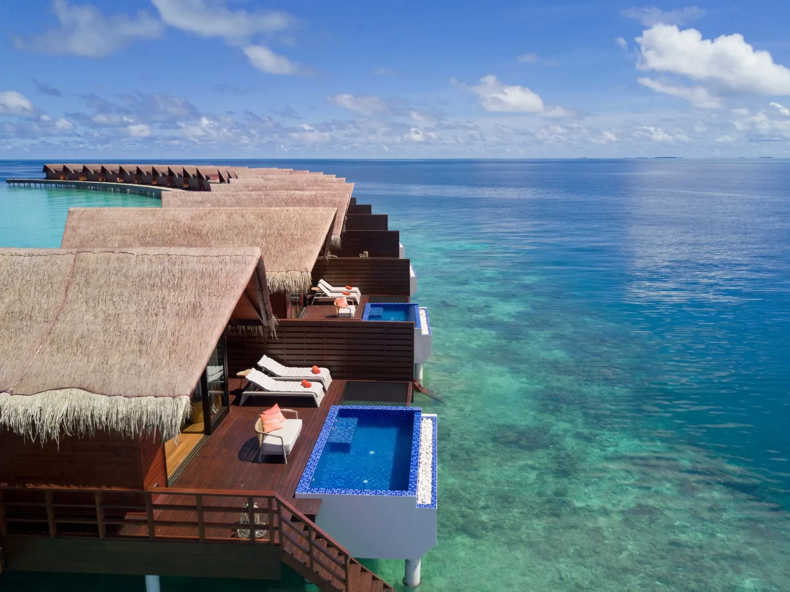 The Reef Pool Water Villas from above, the pools on their decks and the reef dropping away beneath them.