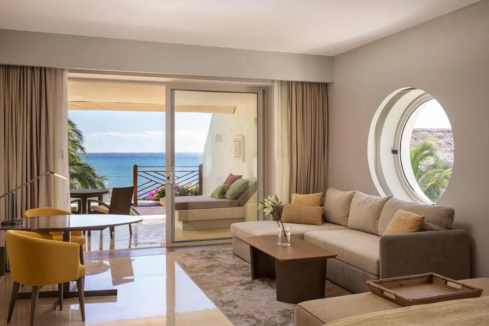 Ambassador Pool Suite living room with a round window and sea-facing terrace