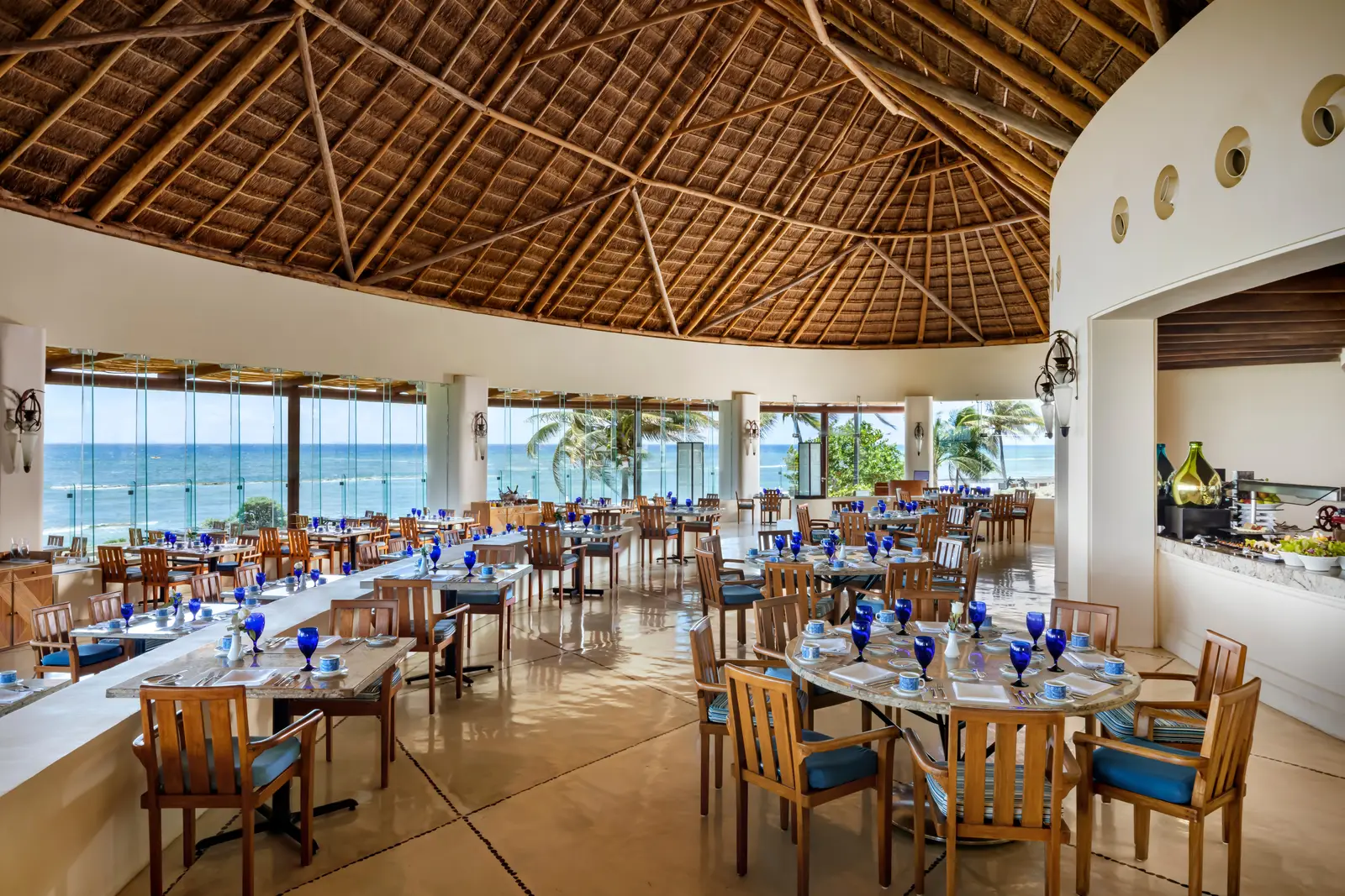 Tables beneath Azul’s palapa roof, open towards the sea