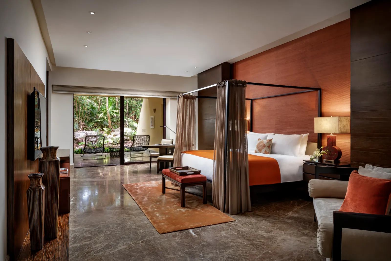 Four-poster bed and windows onto greenery in the Zen Grand Presidential Suite
