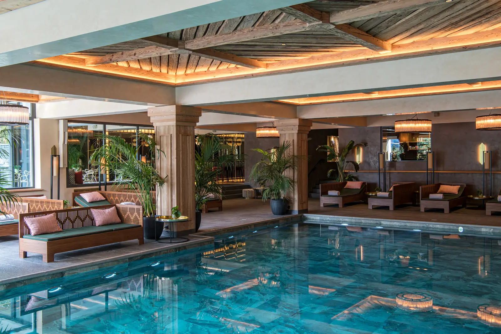 The spa’s indoor pool: pale blue tiles, columns, loungers with pink cushions, palms and a lit timber ceiling