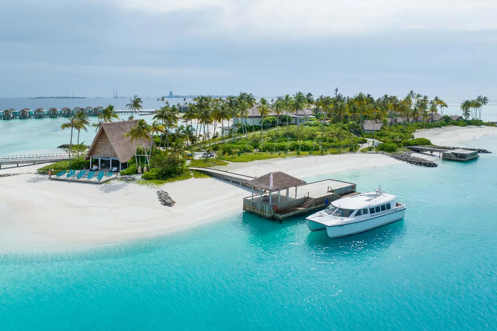 The arrival jetty from the air: a speedboat moored, the A-frame pavilion and the white beach