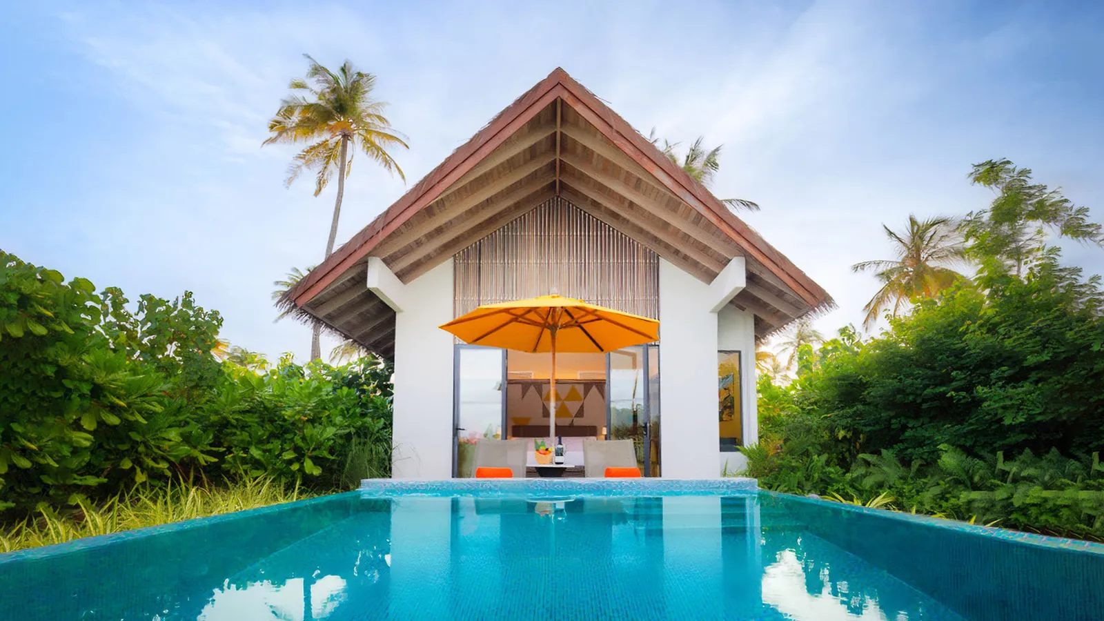 A Gold Beach Private Pool Villa: the pool before its peaked-roof pavilion and an orange parasol