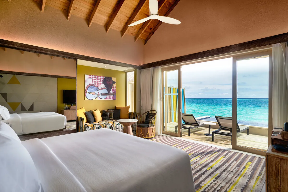 A Platinum Overwater Pool Villa bedroom, loungers on the deck and the sea