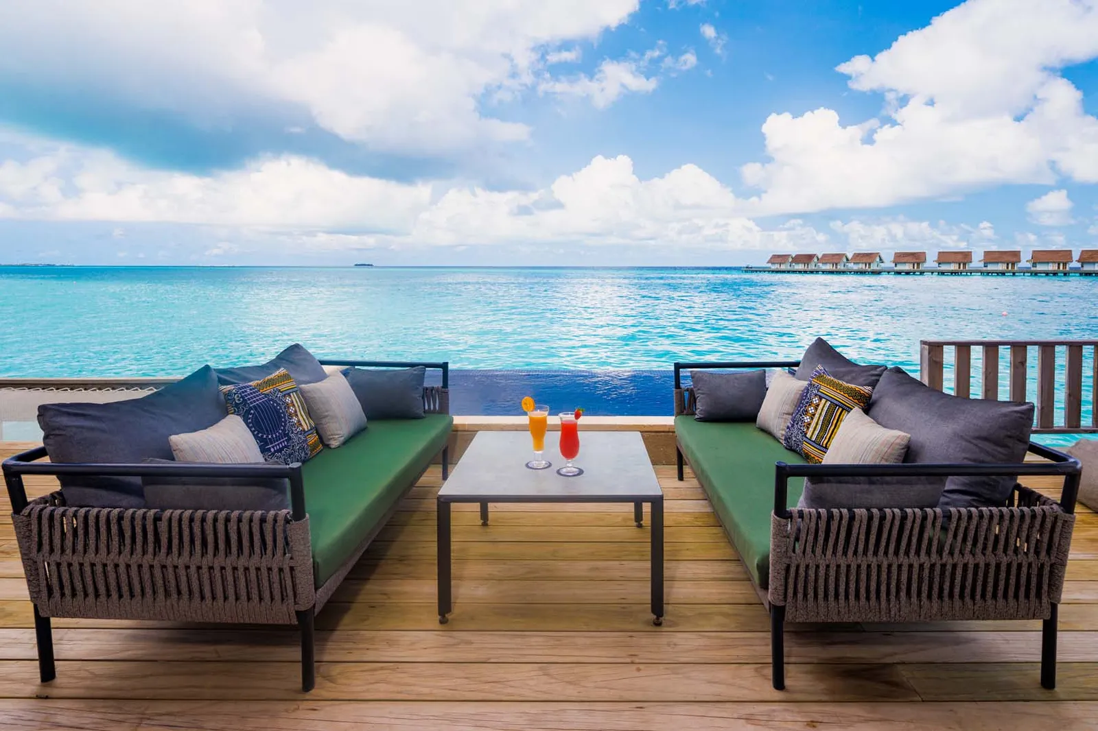 The Rock Royalty villa’s deck: 2 green sofas, 2 cocktails and the infinity pool above the sea