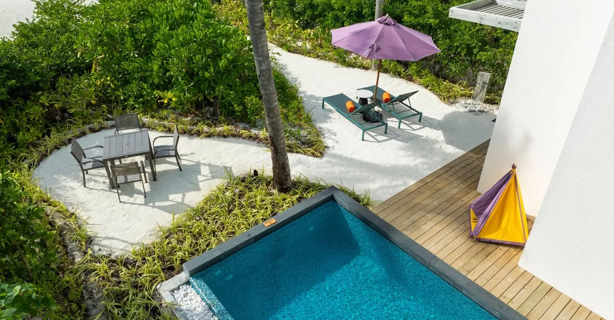 A Silver Family Pool Suite’s pool on its wooden deck, a small yellow tent for the children and the sand garden