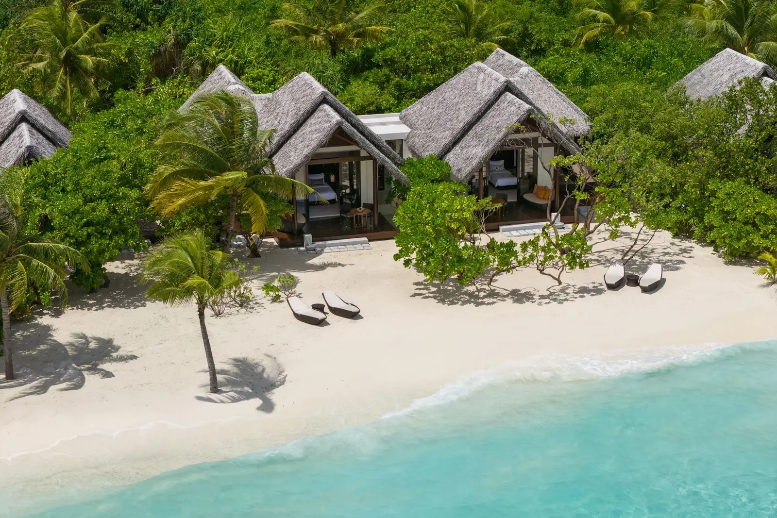 Beach villas with verandas, loungers and palms