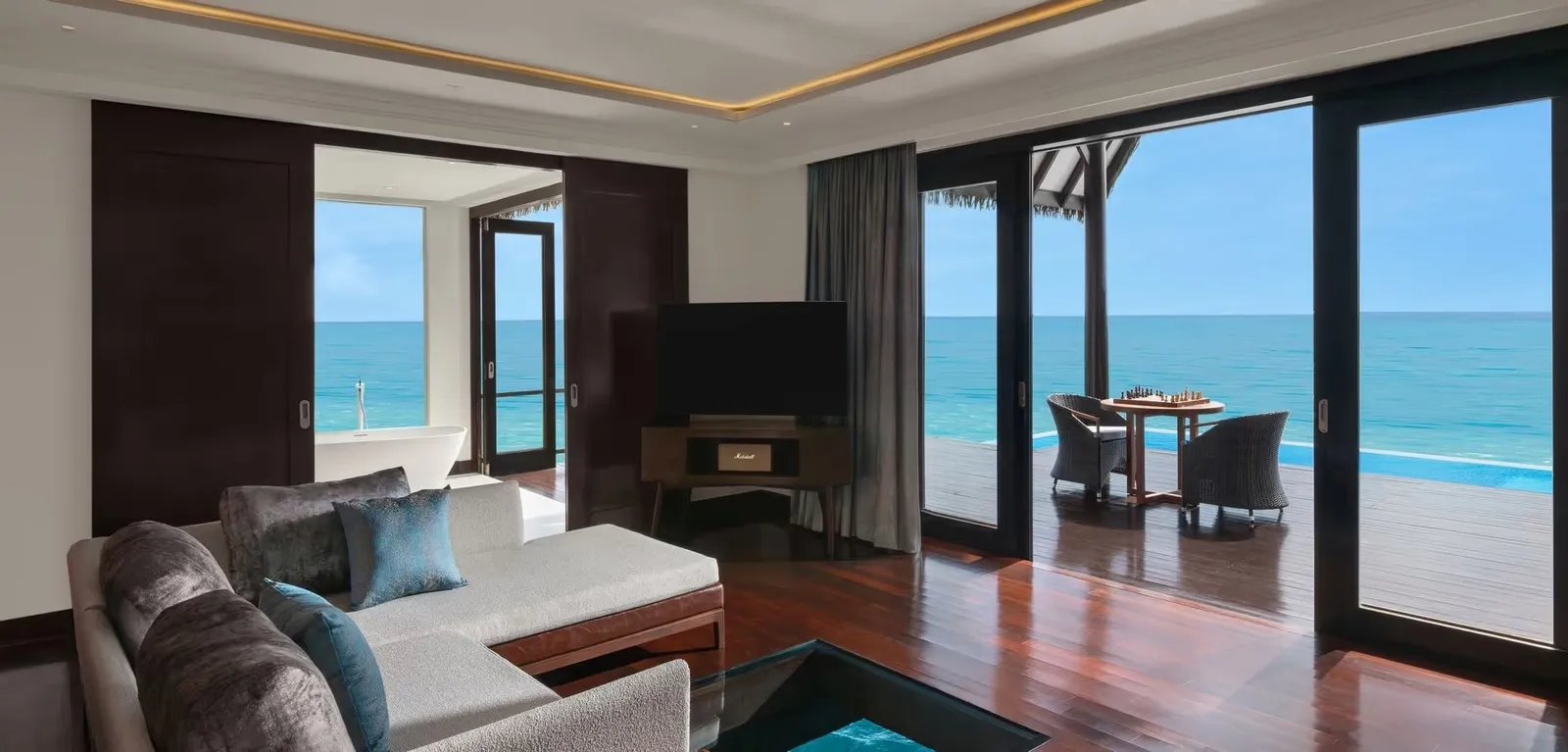 Ocean Suite bedroom and dining area with pool beyond the doors