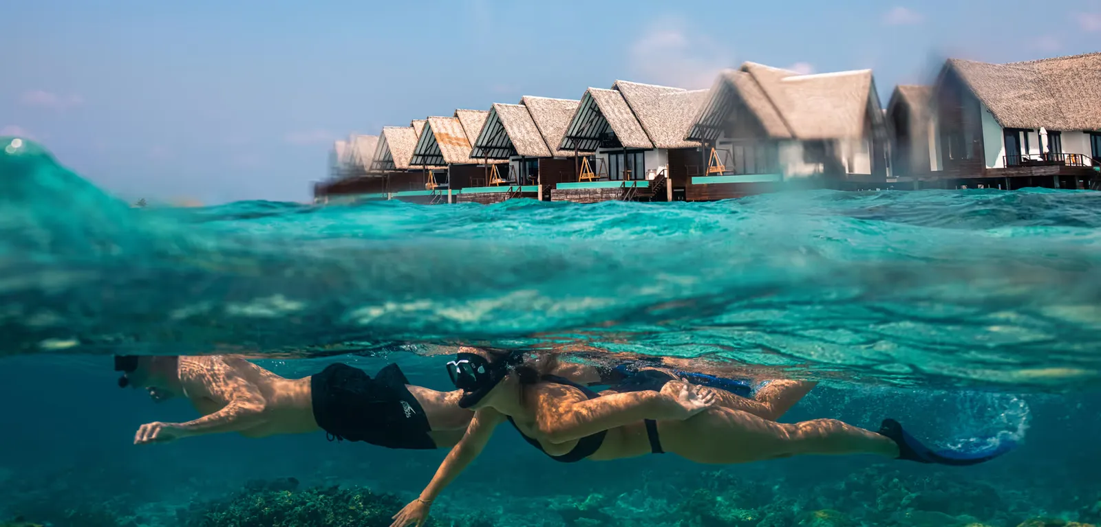 Promotional photograph of 2 snorkellers with villas behind