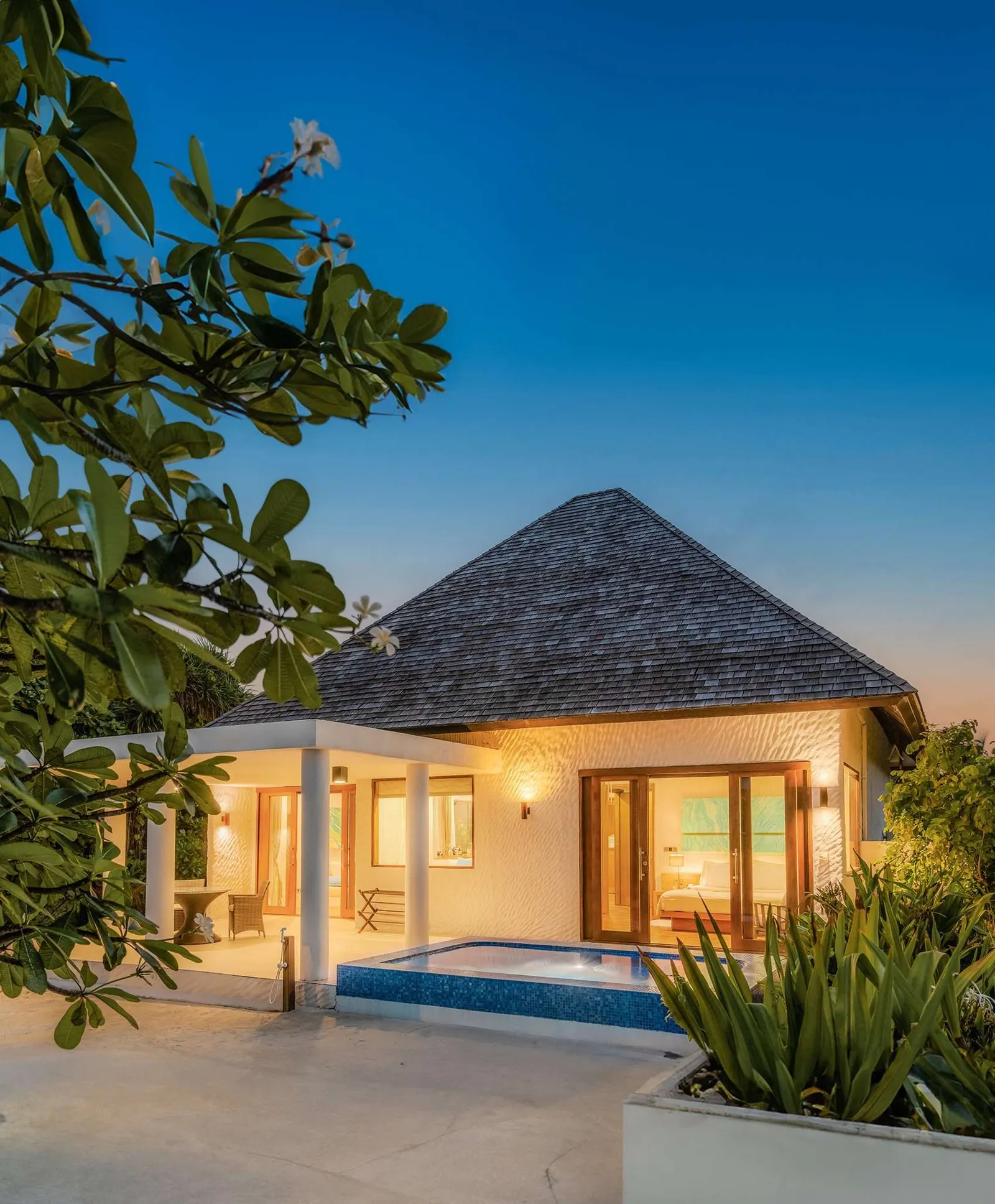 Exterior at dusk with lit villa and compact rectangular pool.