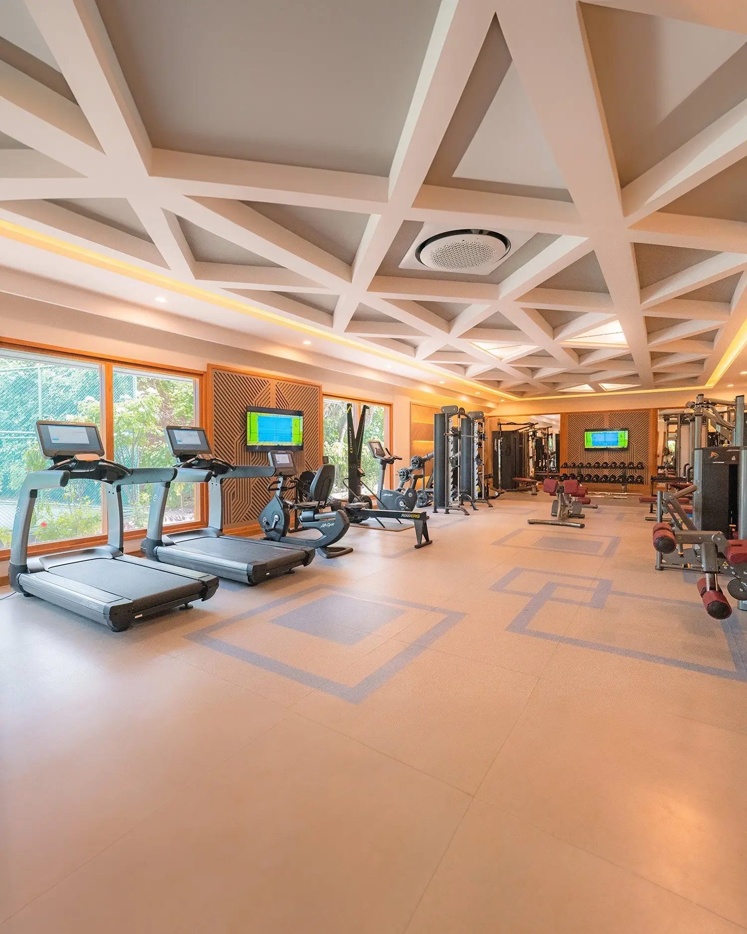 Fitness equipment and treadmills beneath the geometric ceiling.