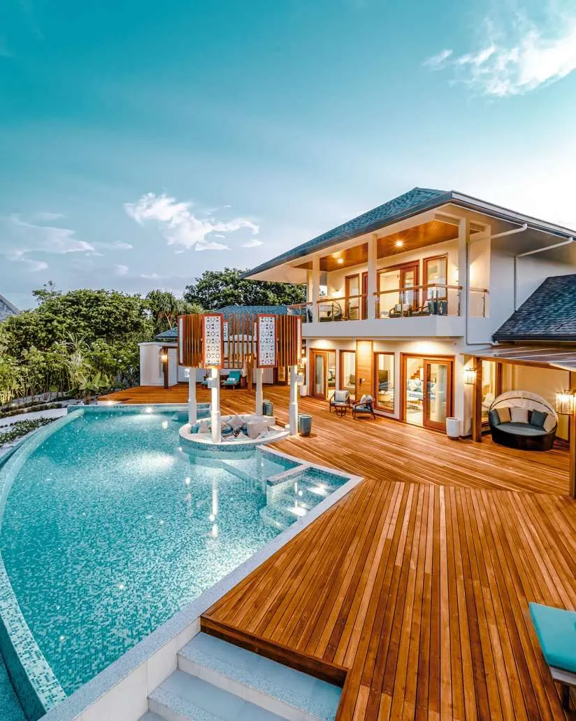 2-storey beachfront residence with curved pool, white columns and sunken seating pavilion.