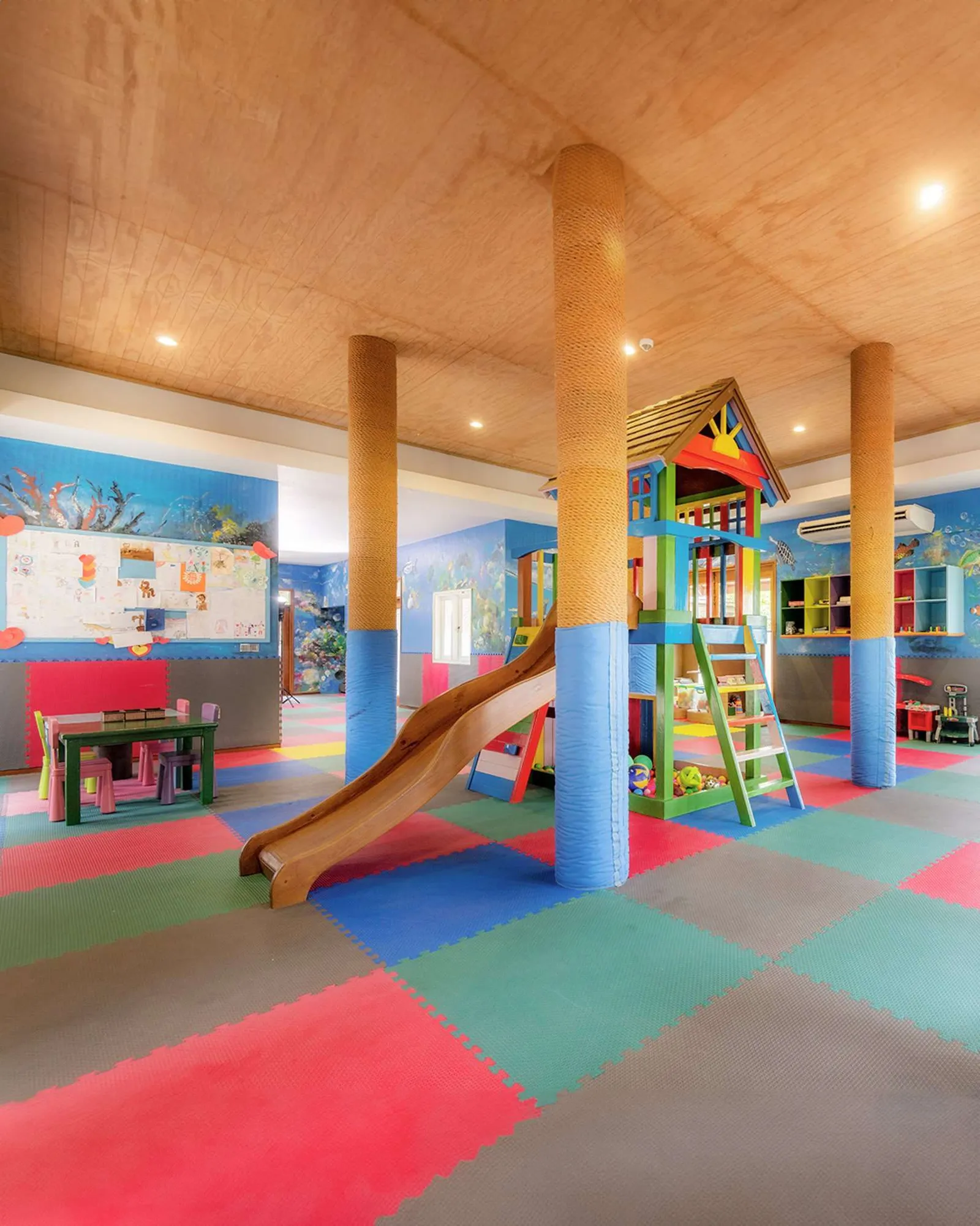 Tender Hearts’ room with a slide, small tables and coloured flooring.