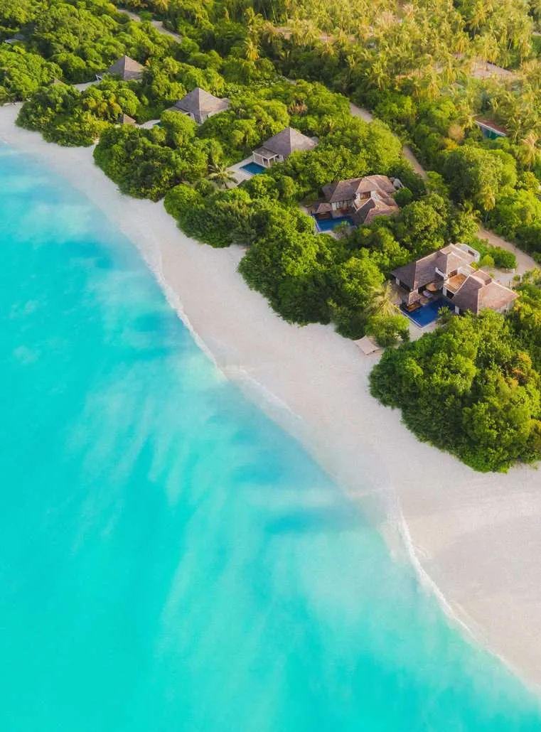 Wide coastline aerial with multiple beach villas and pools; source-category page context only.