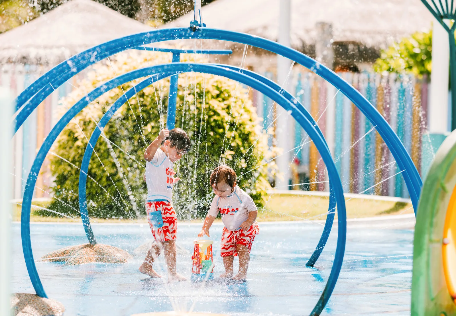 2 children play under the jets of the kids’ club mini splash park.