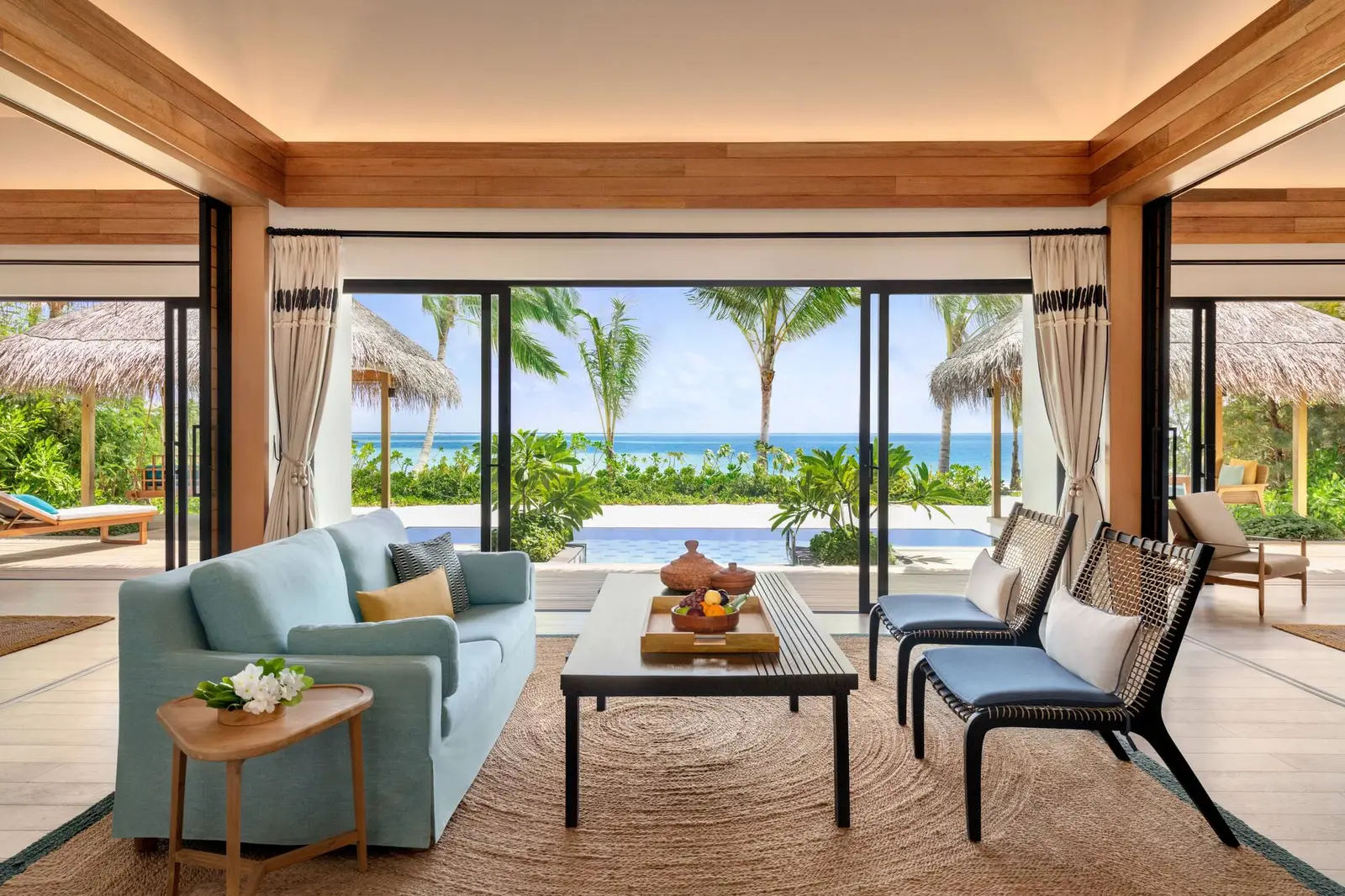 The living room of the Two Bedroom Beach Pool Villa, open to the pool, the garden and the beach.