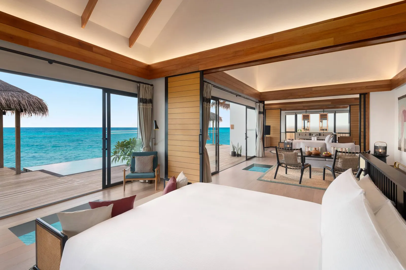 A bedroom of the Two Bedroom Overwater Pool Villa, its bed and windows on the deck and the sea.