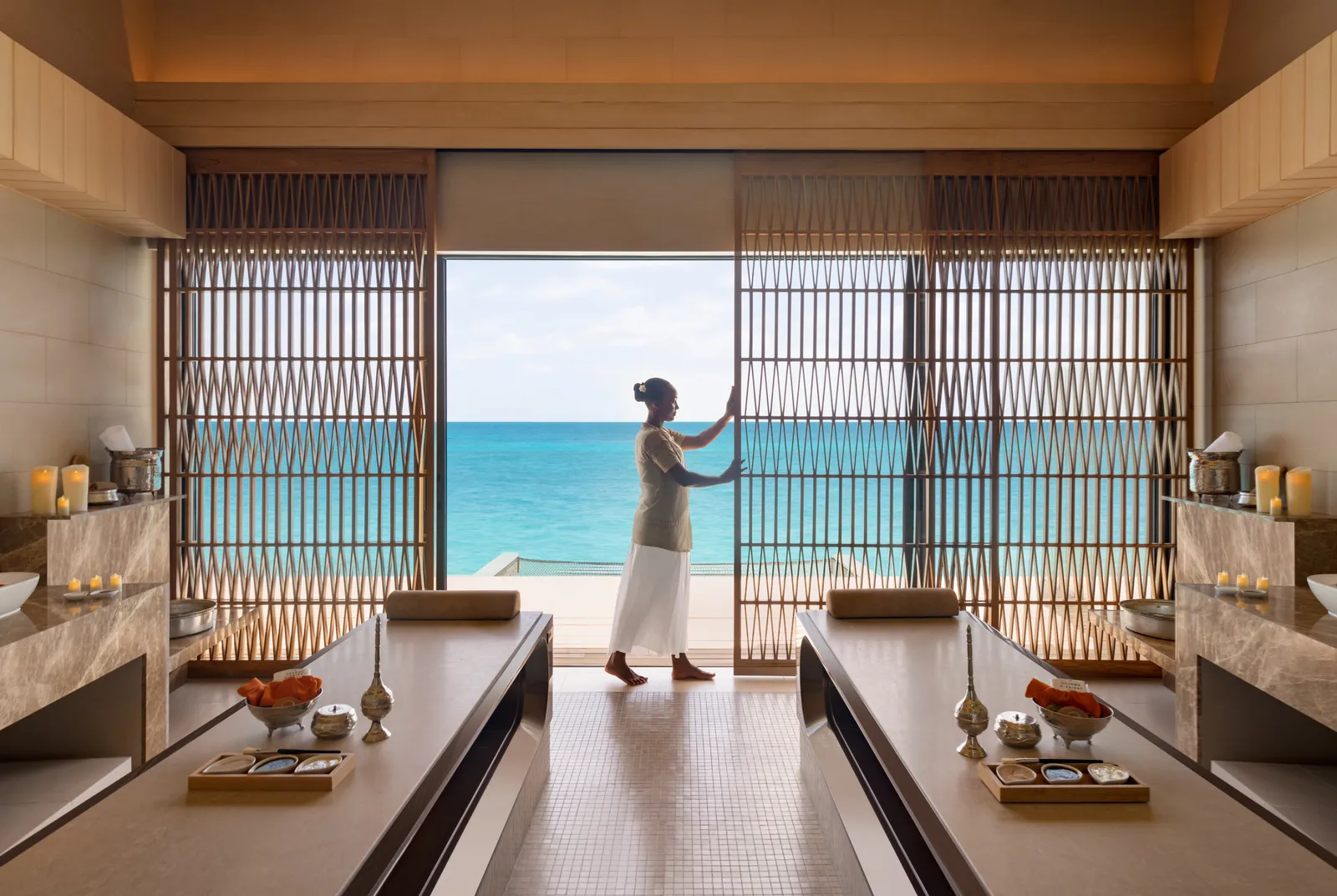 An Amingiri Spa & Hammam room with 2 beds and its slatted door open to the sea.