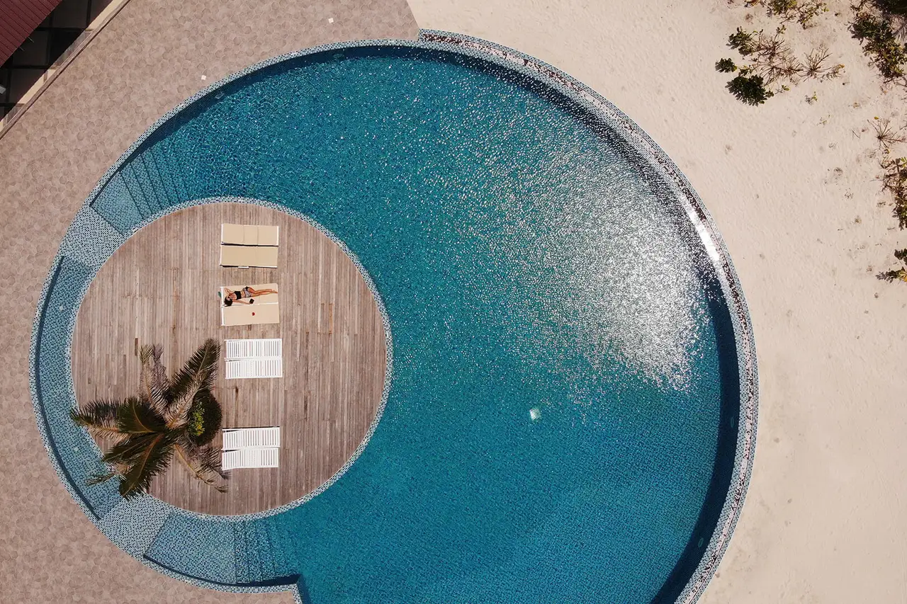 La piscina rotonda vista dall’alto, con la sua isola di legno al centro e i lettini.