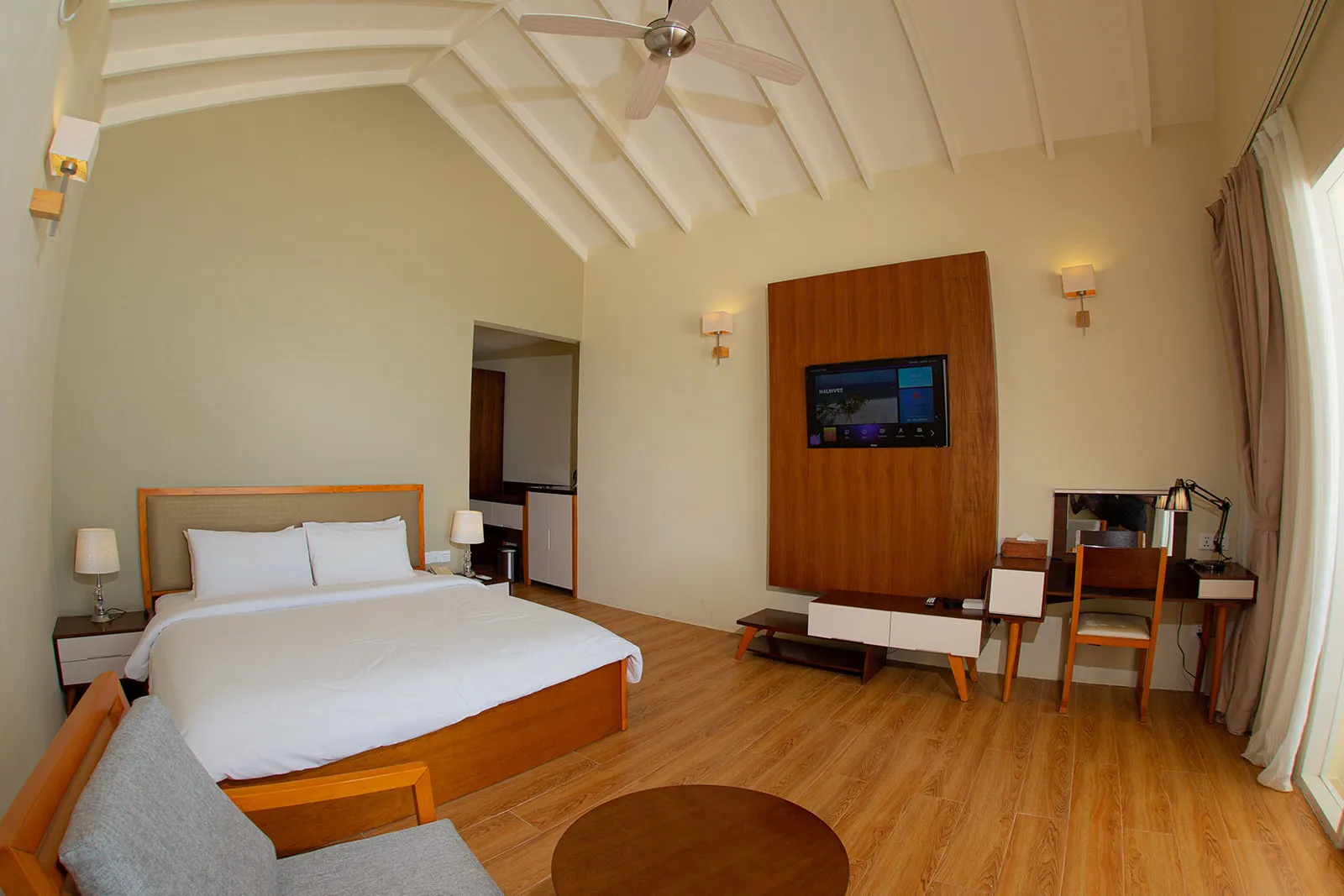 Una camera da letto con il letto matrimoniale, il televisore su un pannello di legno e la scrivania, come la mostra la pagina del Family Bungalow.