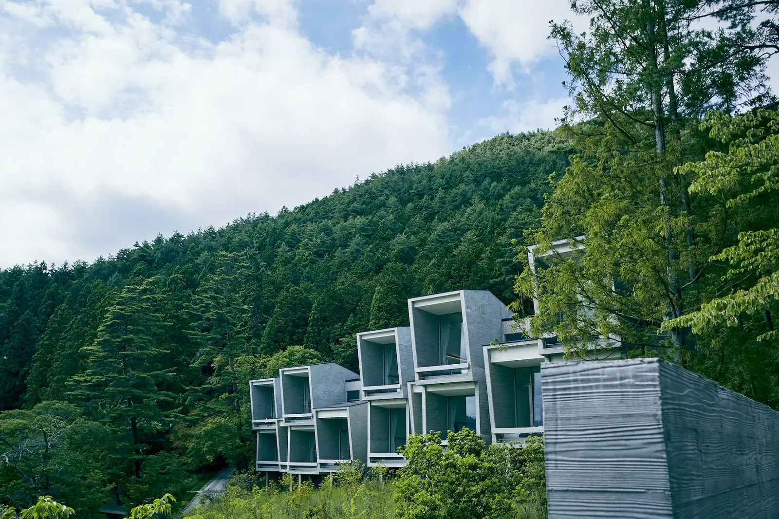 The concrete cabins stacked on the forested slope above the lake