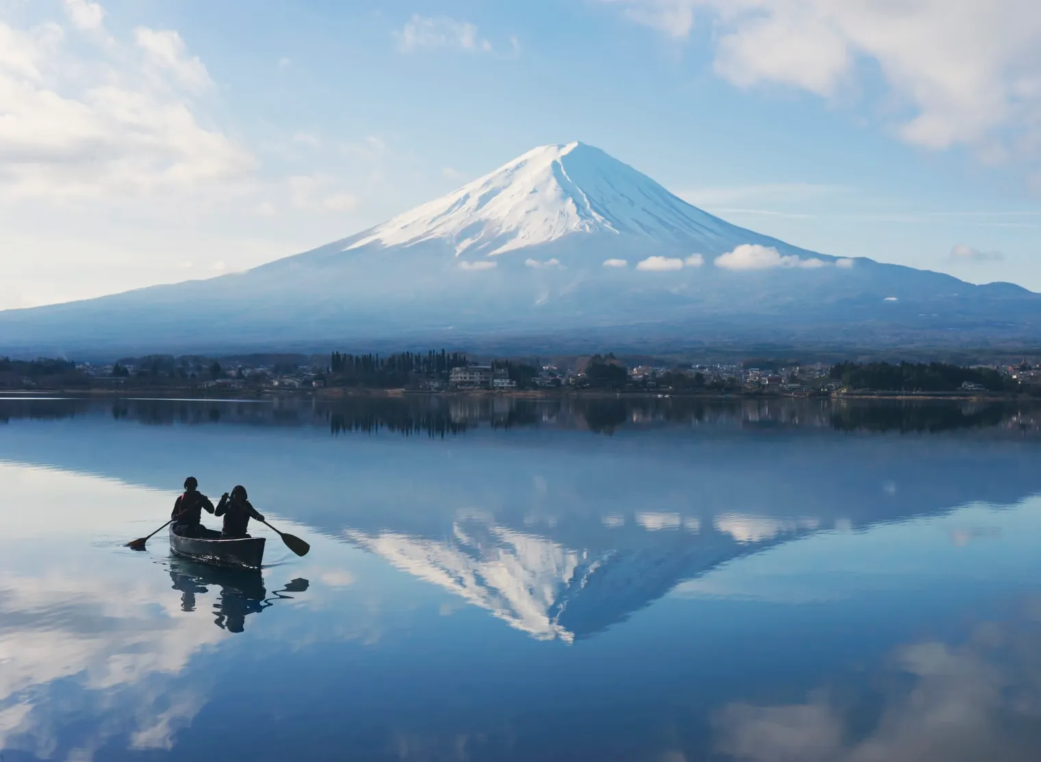 A canoe on the still lake at dawn, Mount Fuji reflected in the water