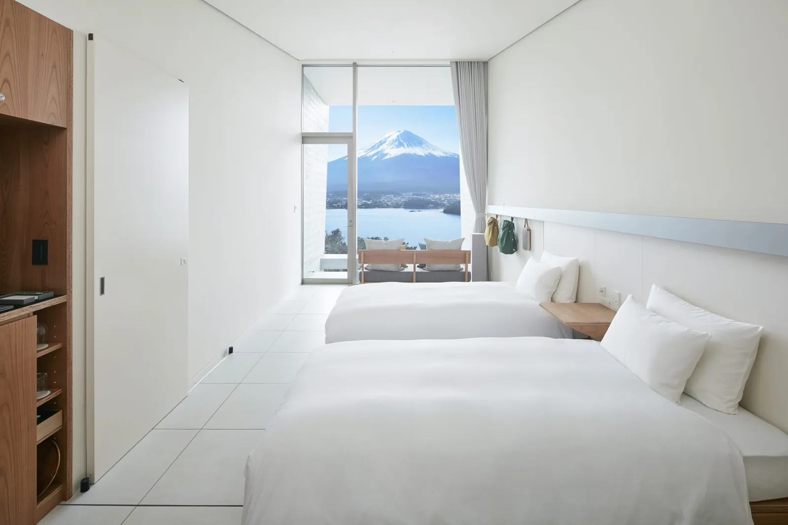 2 single beds in a white cabin, the glass wall framing the lake and Mount Fuji