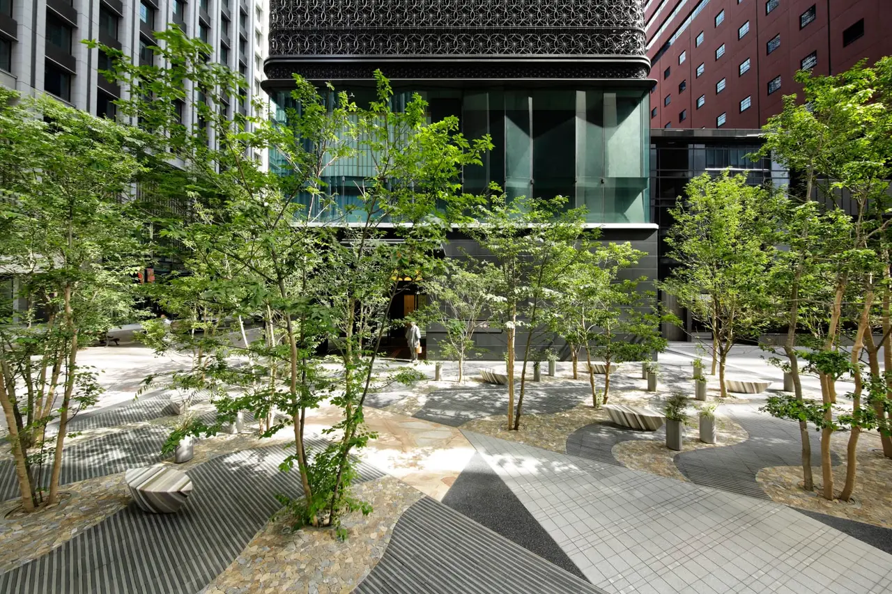 The garden in front of the hotel, with maples, banded paving and the towers of the business district.