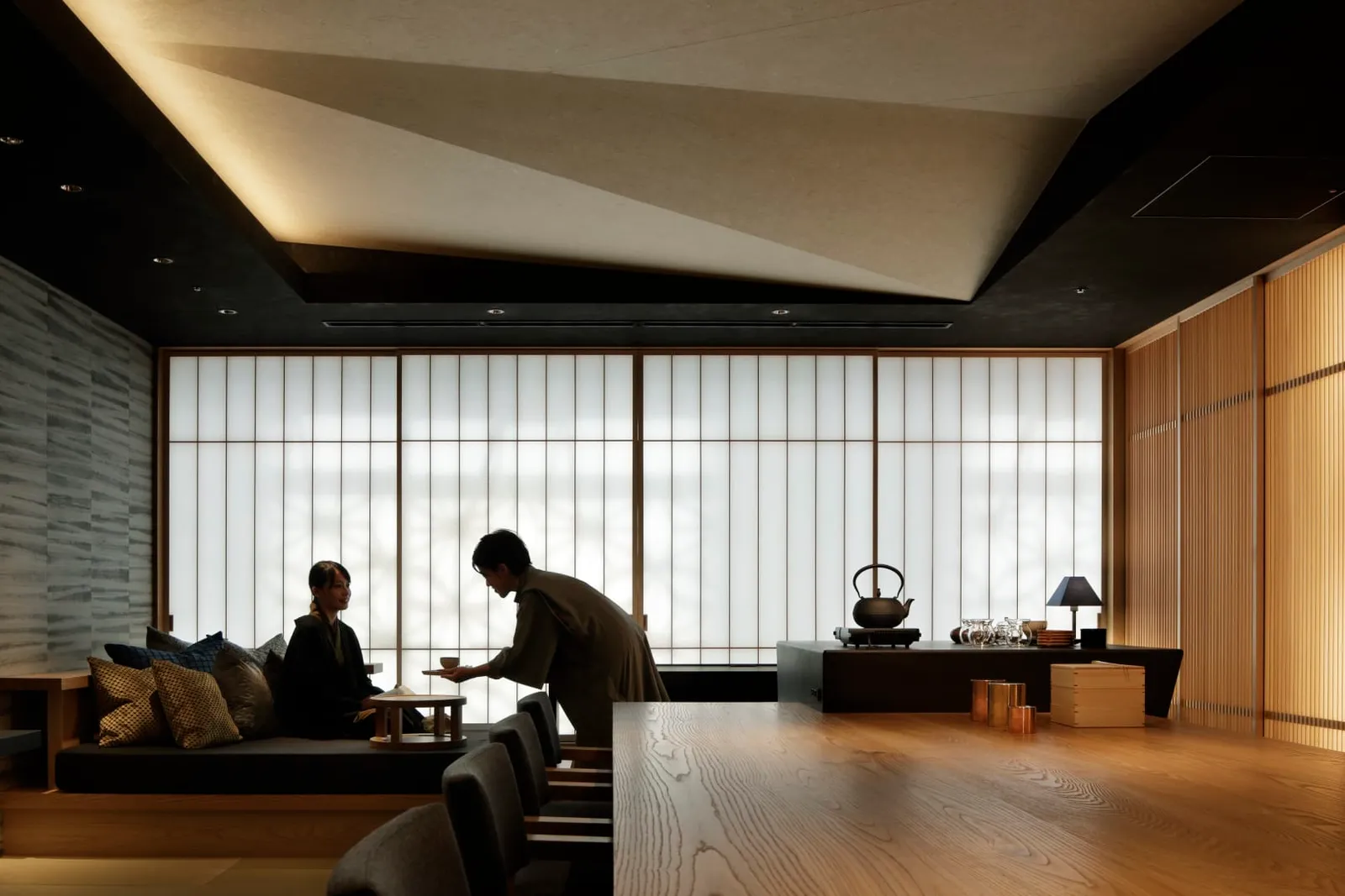The OCHANOMA Lounge in the afternoon, guests on the low sofas and a host bringing tea.