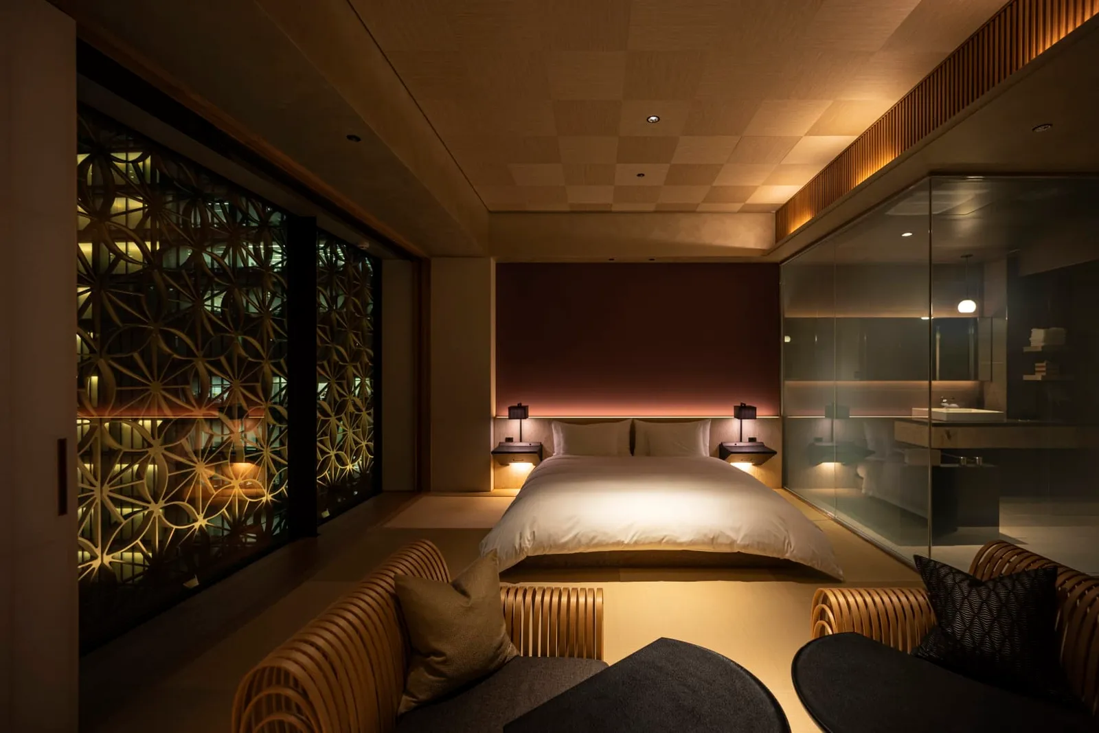 A Yuri room at night, with the king-size bed on the tatami, the glass bathroom and the lit facade lattice.