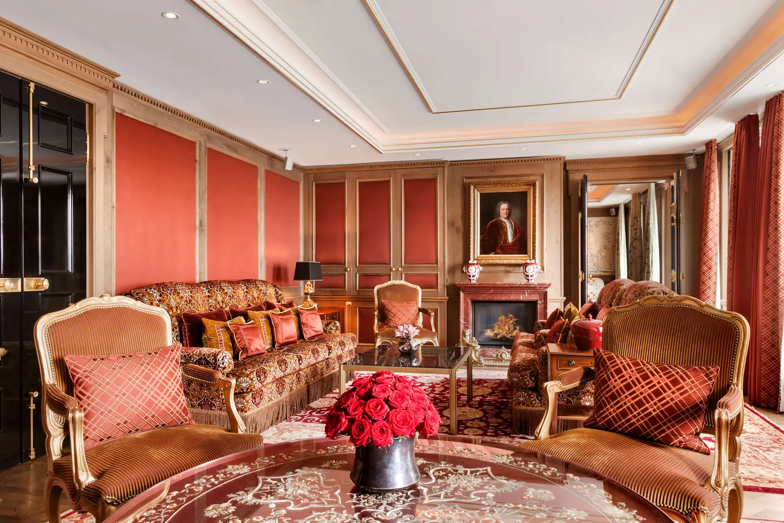 Imperial Suite with red walls, gold-patterned sofas, a fireplace and roses on the table.