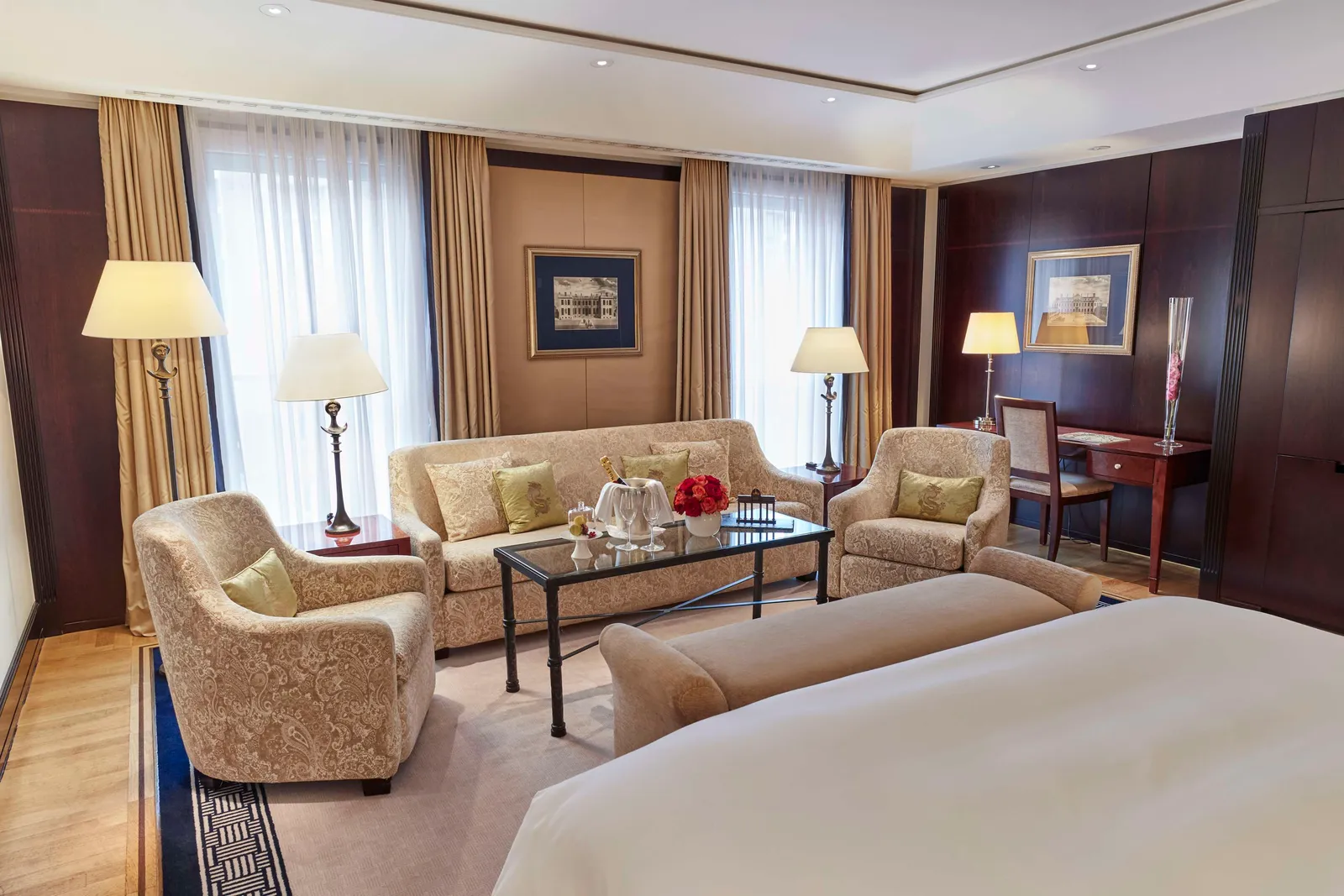 Junior Suite with a bed, sofa and armchairs around a coffee table.
