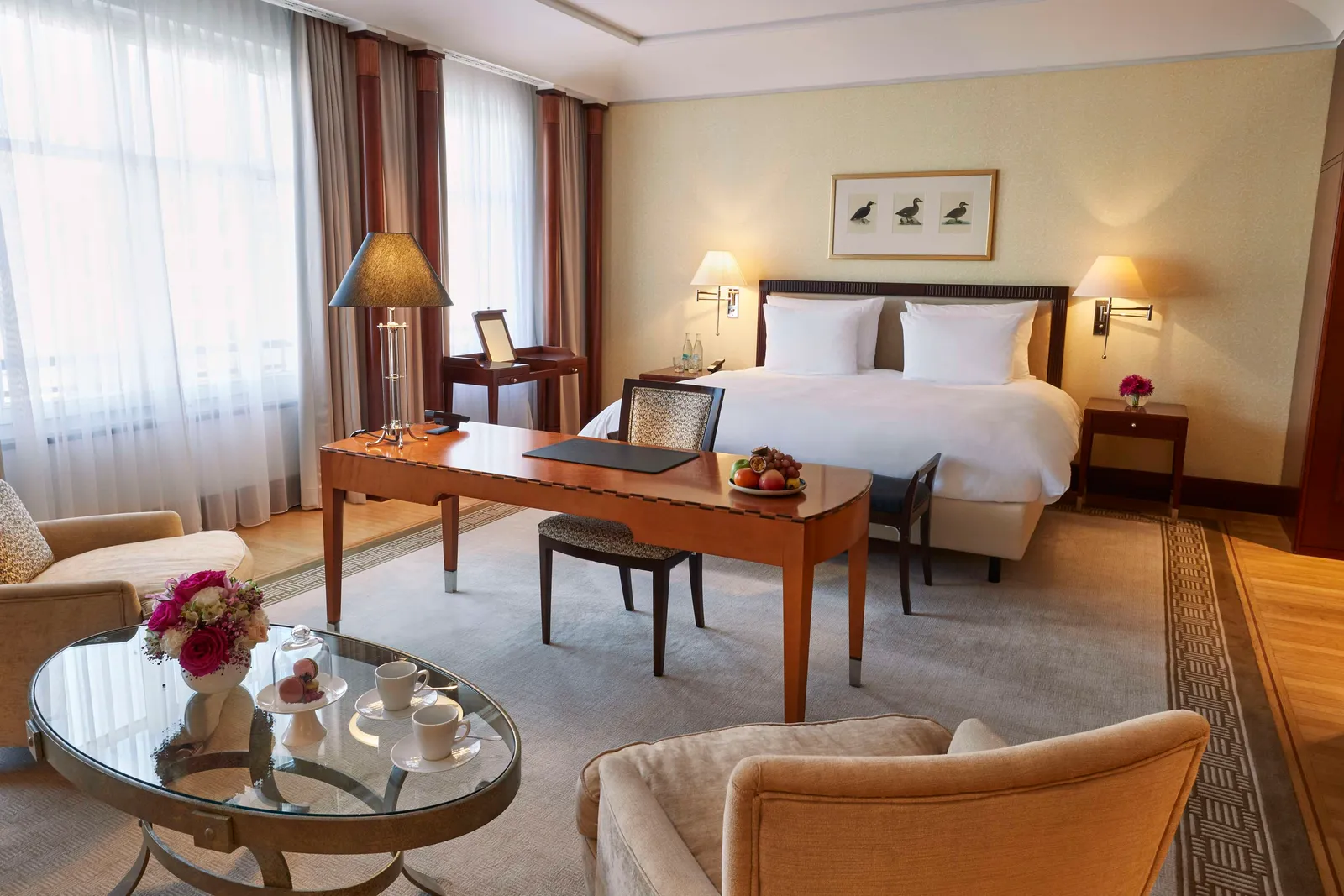 Junior Suite Unter den Linden with a desk in front of the bed and armchairs beside the window.