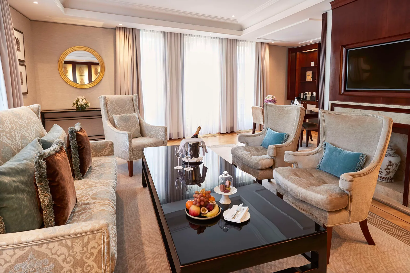 The Linden Suite living room with a sofa, pale armchairs and fruit and flowers on the coffee table.