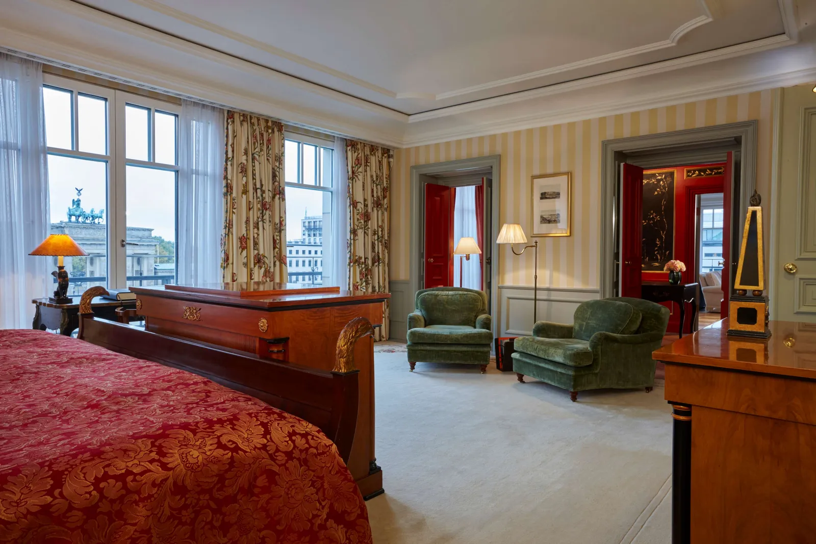 Royal Suite with a red bedcover, green seating and the Brandenburg Gate beyond the windows.