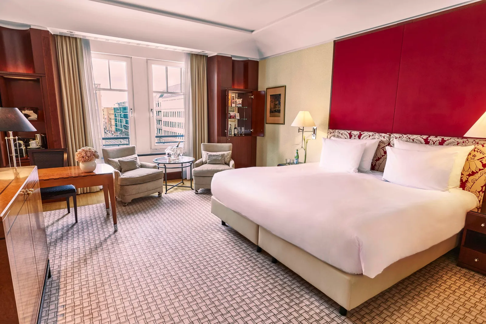 Superior Deluxe Room with a red headboard and seating beside the windows.