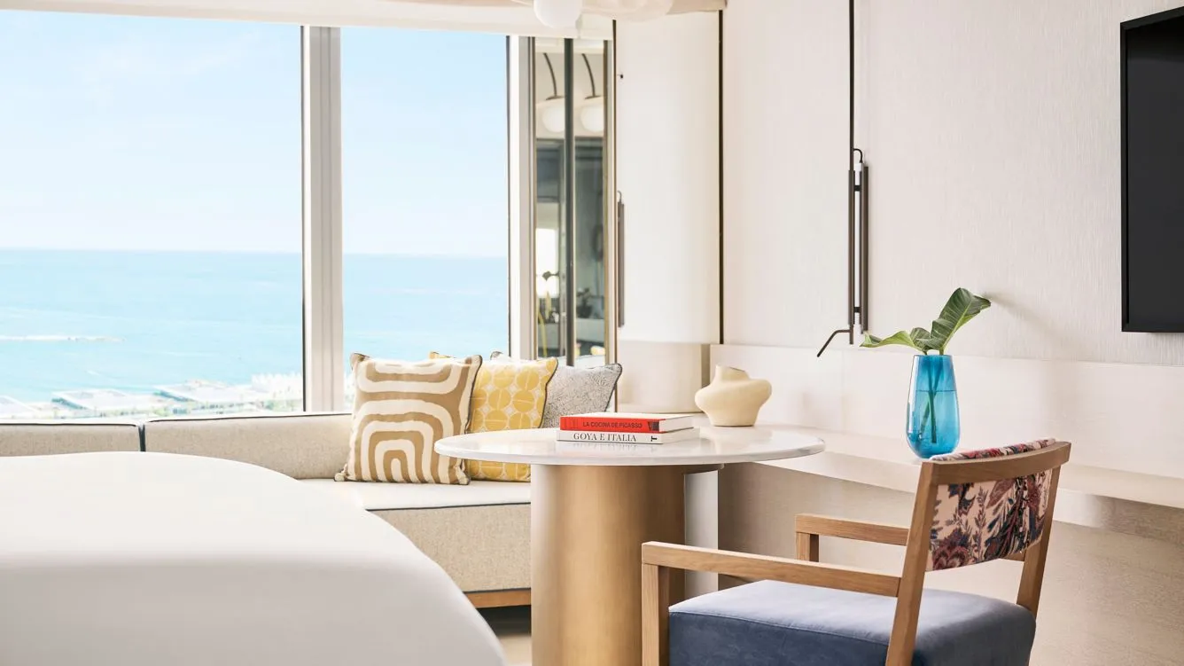 A table, armchair and sea through a room window