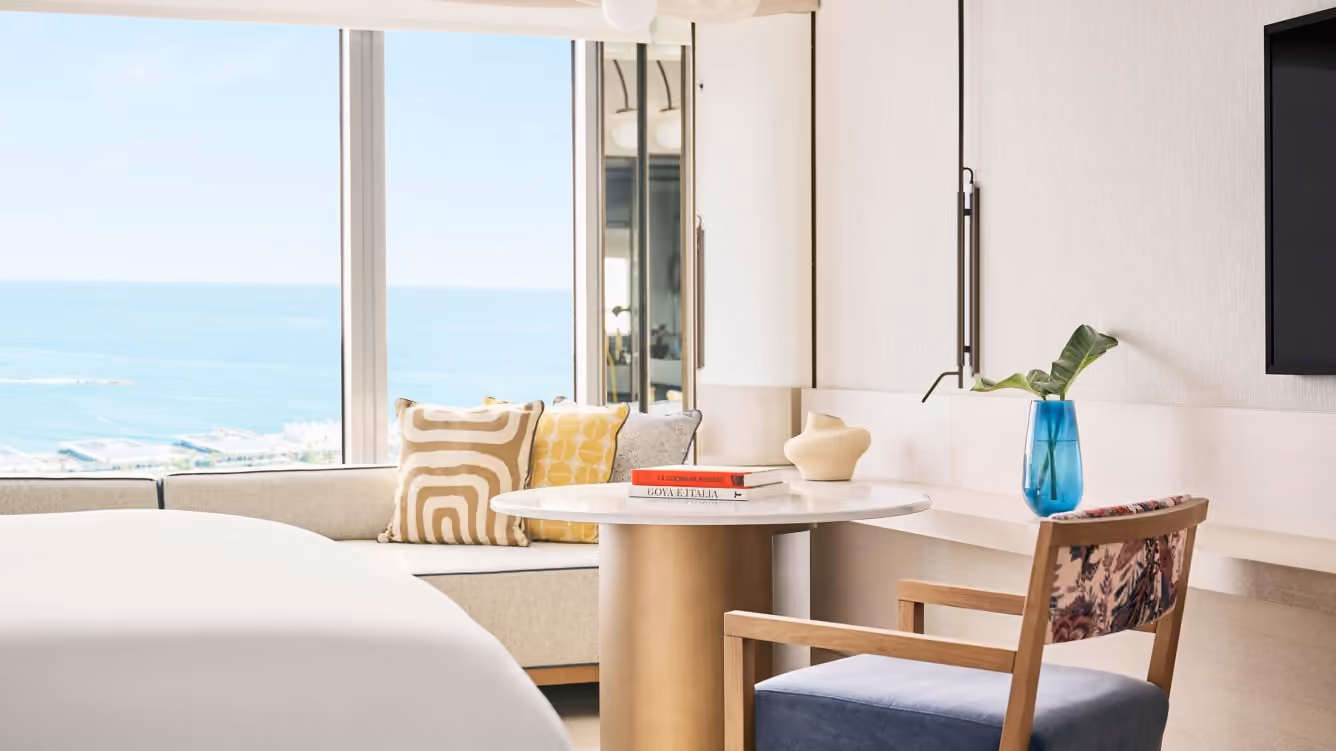 A table, armchair and sea through a room window
