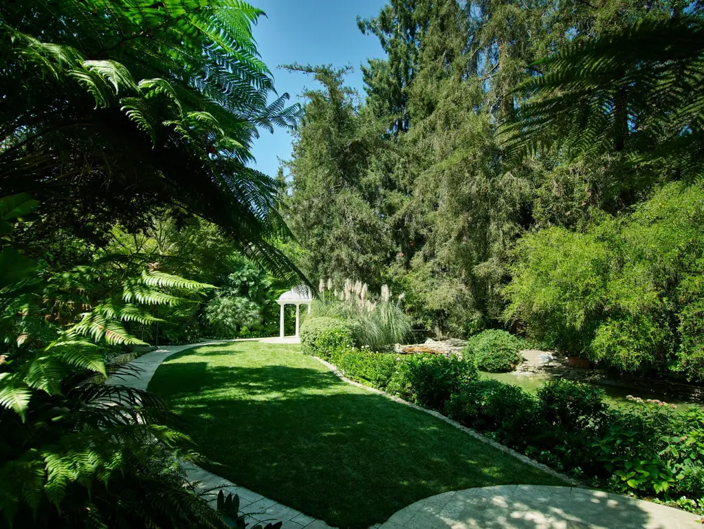 The garden lawn with the white gazebo at the end, tall trees around